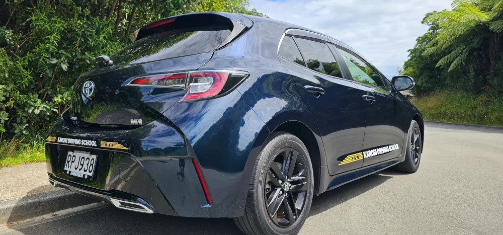 Exterior of a dark blue Toyota Corolla Sport with Karori Driving School signage.